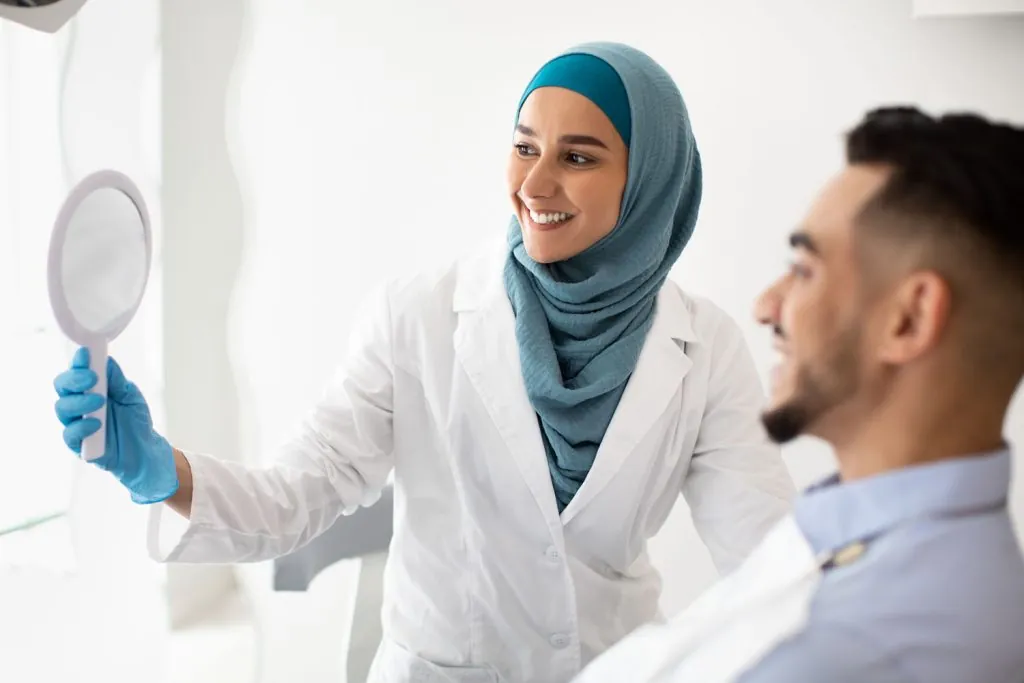 muslim dentist woman holding mirror showing teeth 2026 03 24 02 21 22 utc 1