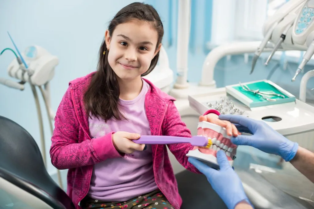 girl in dentist chair showing proper tooth brushin 2026 01 07 00 59 04 utc