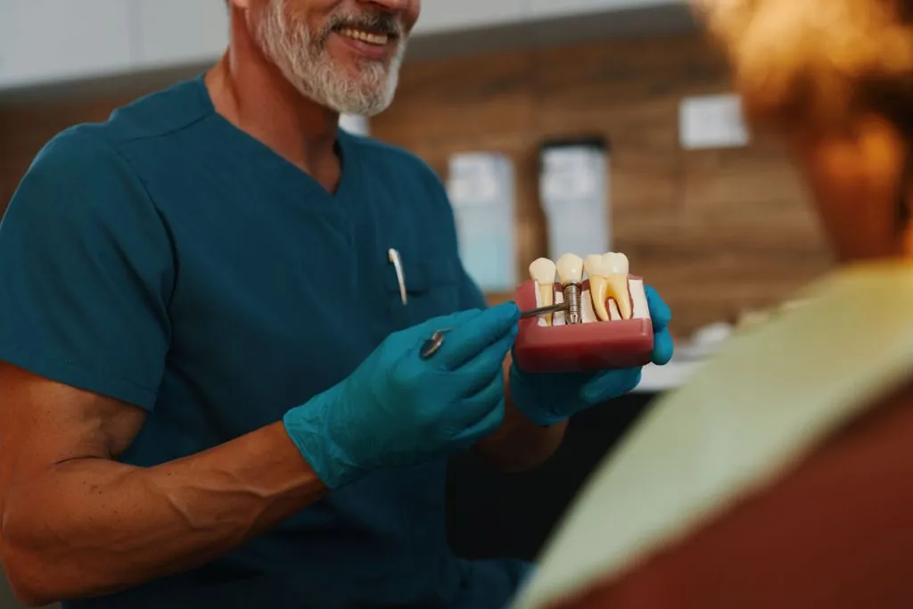 smiling dentist displaying dental implants to fema 2026 03 18 05 36 51 utc